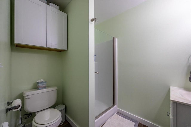 bathroom featuring vanity, a shower with shower door, and toilet