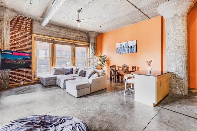 living room with concrete flooring, ceiling fan, and decorative columns