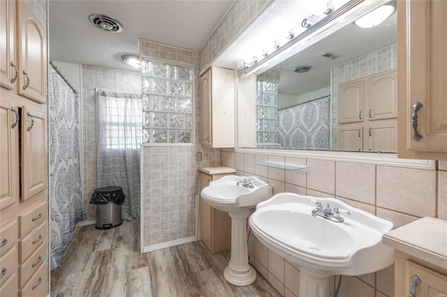 bathroom featuring tile walls, sink, backsplash, wood-type flooring, and a textured ceiling