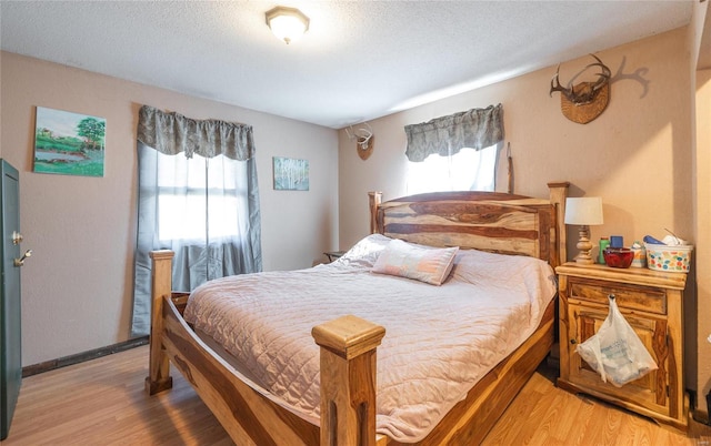 bedroom with multiple windows, a textured ceiling, and light hardwood / wood-style flooring