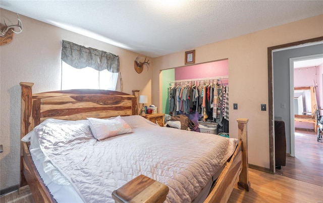 bedroom with a closet, hardwood / wood-style floors, and a textured ceiling