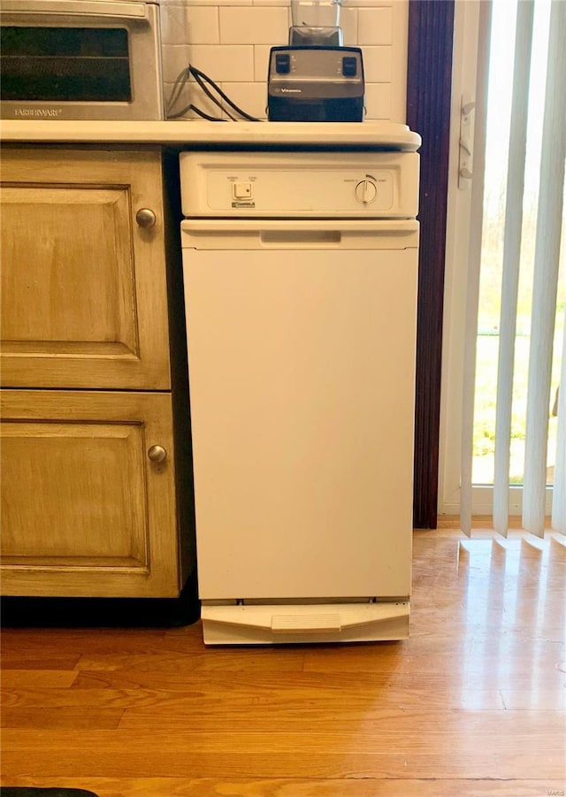 interior space featuring backsplash, dishwasher, and light wood-type flooring