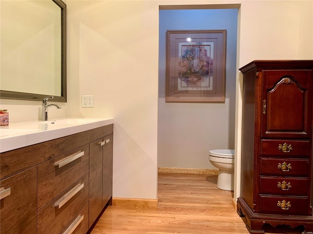 bathroom with wood-type flooring, vanity, and toilet