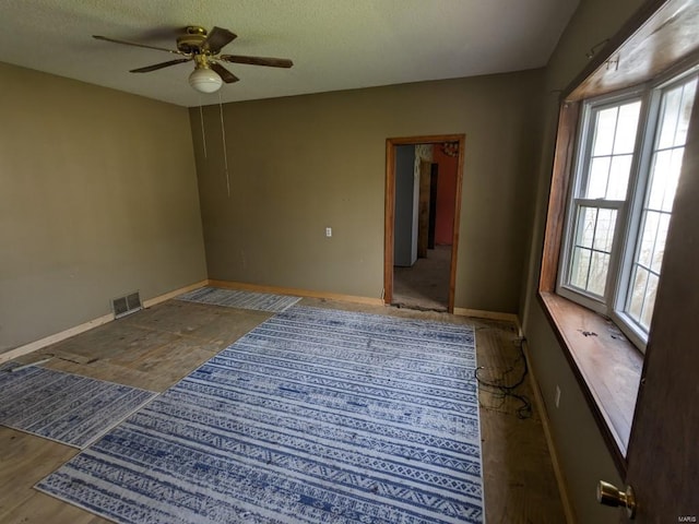 empty room featuring ceiling fan, a wealth of natural light, and dark hardwood / wood-style floors