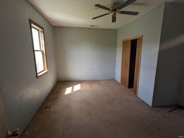 unfurnished room featuring carpet, ceiling fan, and a textured ceiling