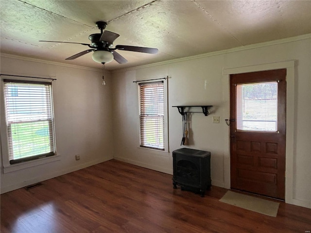 foyer with a wealth of natural light, a wood stove, ceiling fan, and dark hardwood / wood-style flooring