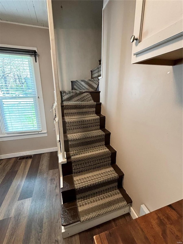 staircase featuring dark wood-type flooring and ornamental molding