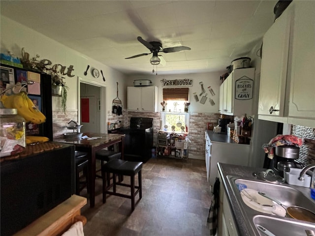 kitchen featuring white cabinets, dark tile flooring, ceiling fan, and sink