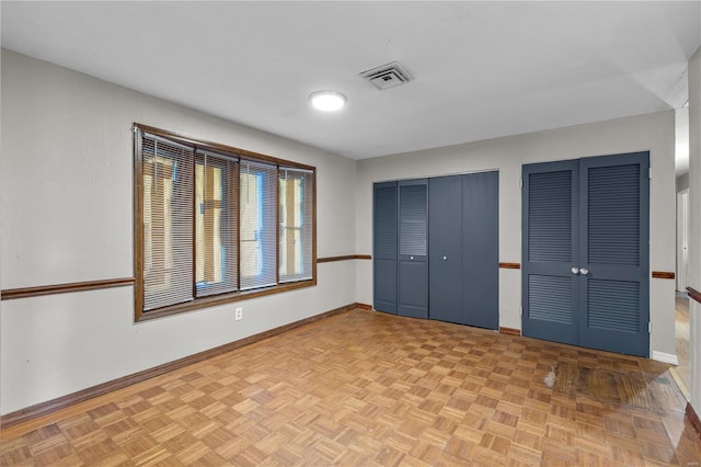 unfurnished bedroom with light parquet flooring and two closets