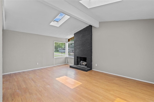 unfurnished living room featuring vaulted ceiling with skylight, light wood-type flooring, brick wall, and a fireplace