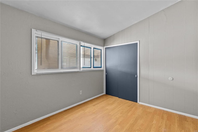 unfurnished bedroom with lofted ceiling, a closet, and light wood-type flooring