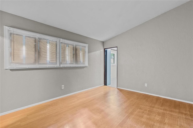 empty room with lofted ceiling and light hardwood / wood-style floors