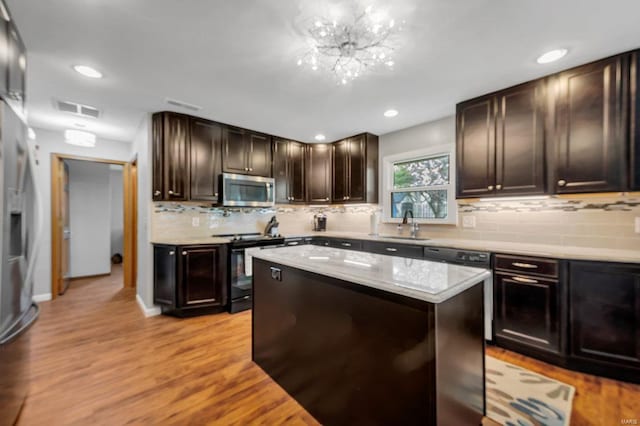 kitchen with a kitchen island, range, dark brown cabinets, a chandelier, and light hardwood / wood-style flooring