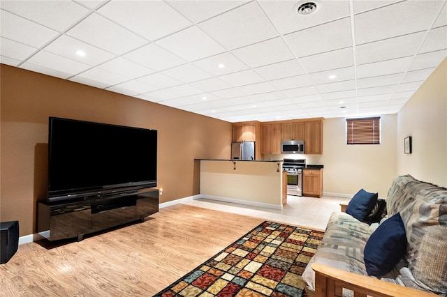 living room featuring light hardwood / wood-style flooring and a drop ceiling