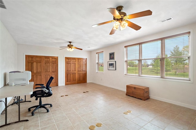 unfurnished office with ceiling fan and light tile flooring