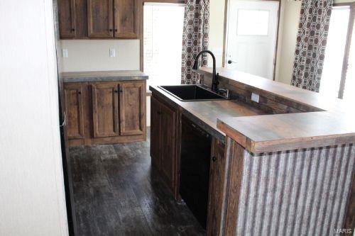 kitchen with sink, black dishwasher, an island with sink, and dark wood-type flooring