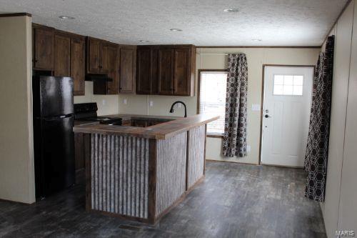 kitchen with black refrigerator, stove, dark brown cabinets, and a textured ceiling