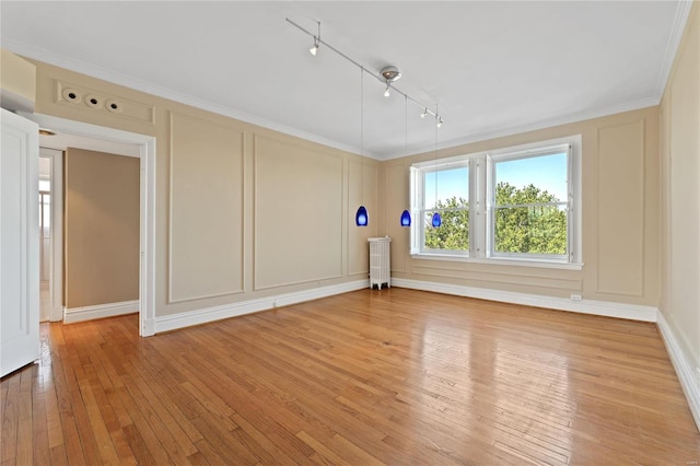 unfurnished room with rail lighting, light hardwood / wood-style floors, ornamental molding, and radiator