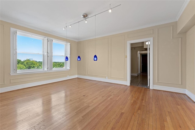 spare room featuring crown molding, rail lighting, and light wood-type flooring