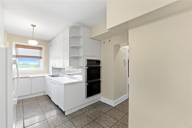 kitchen featuring white cabinetry, decorative light fixtures, white refrigerator, and black double oven