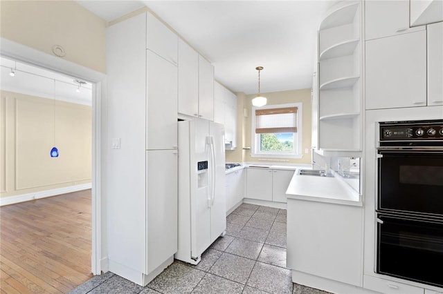 kitchen with white cabinetry, white fridge with ice dispenser, light hardwood / wood-style flooring, and pendant lighting