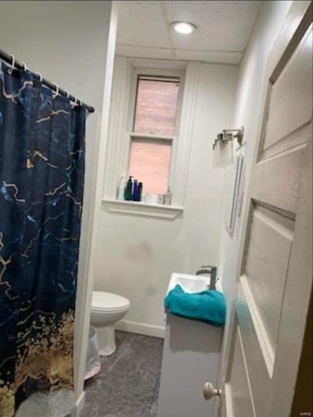 bathroom with toilet, tile floors, and a paneled ceiling