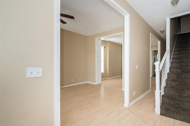 interior space with a textured ceiling, ceiling fan, and light wood-type flooring