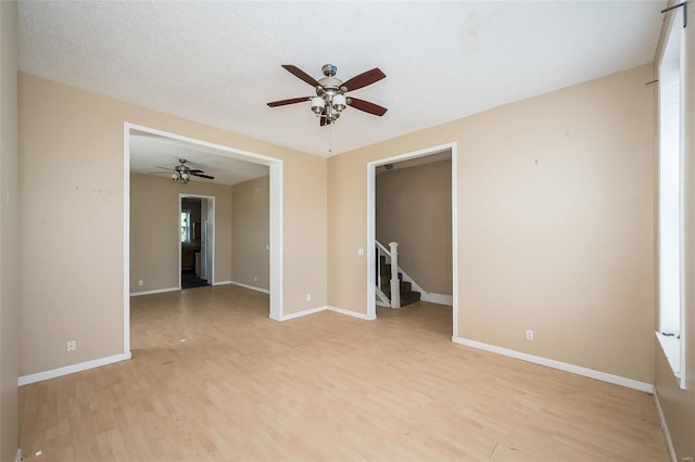 empty room with light hardwood / wood-style floors, ceiling fan, and a textured ceiling