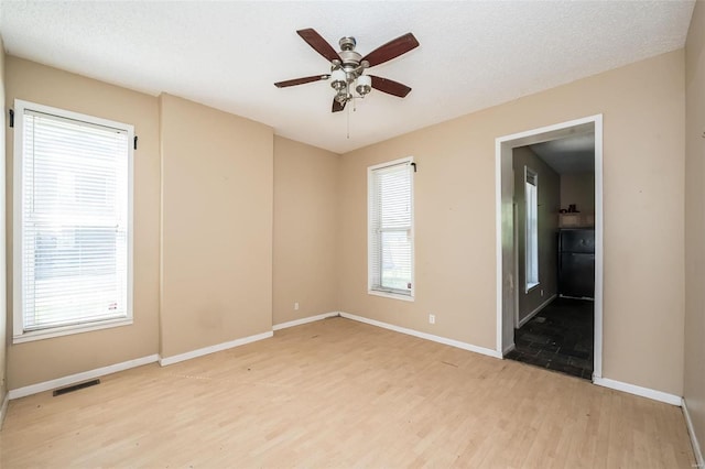 spare room with light hardwood / wood-style flooring, ceiling fan, and plenty of natural light