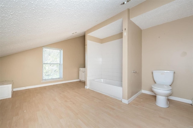 bathroom with wood-type flooring, toilet, and a textured ceiling