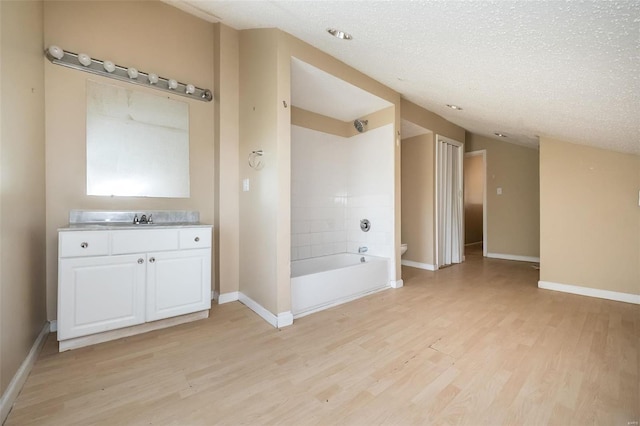 full bathroom featuring oversized vanity, toilet, tiled shower / bath, a textured ceiling, and hardwood / wood-style floors