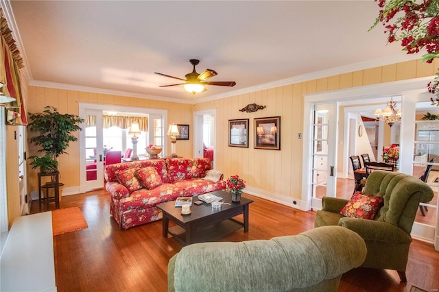 living room with crown molding, ceiling fan with notable chandelier, and hardwood / wood-style floors