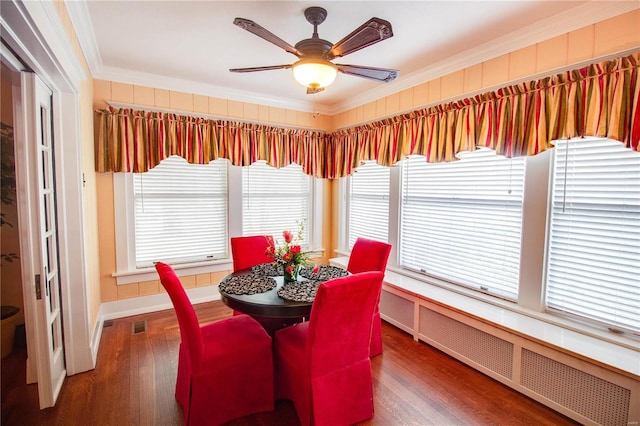 dining space with crown molding, ceiling fan, radiator, and dark wood-type flooring