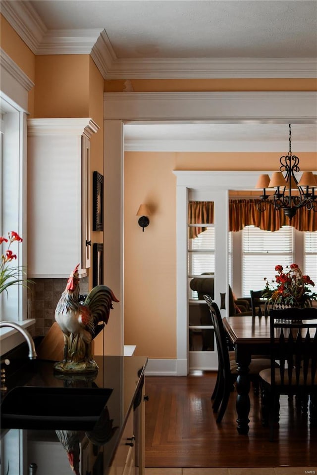 dining area with dark wood-type flooring, ornamental molding, a chandelier, and sink