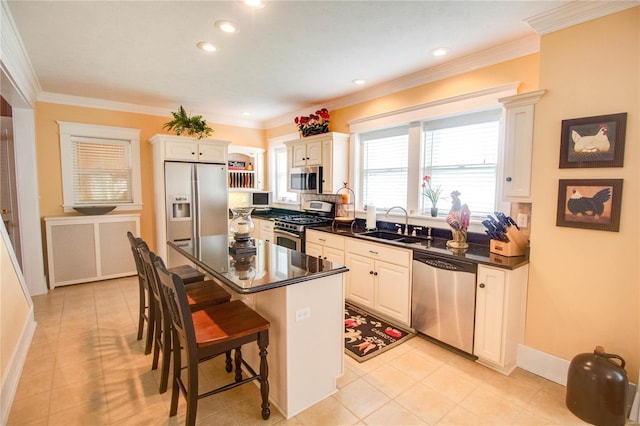 kitchen featuring sink, a center island, appliances with stainless steel finishes, a kitchen breakfast bar, and white cabinets