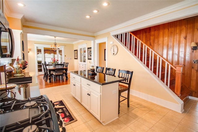 kitchen with white cabinetry, ornamental molding, a kitchen bar, and decorative light fixtures