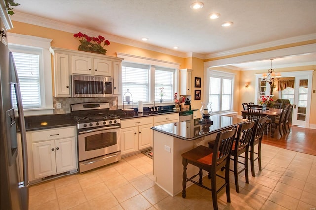 kitchen featuring a breakfast bar, crown molding, a center island, appliances with stainless steel finishes, and decorative backsplash