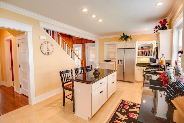 kitchen featuring crown molding, a kitchen bar, stainless steel appliances, white cabinets, and a kitchen island