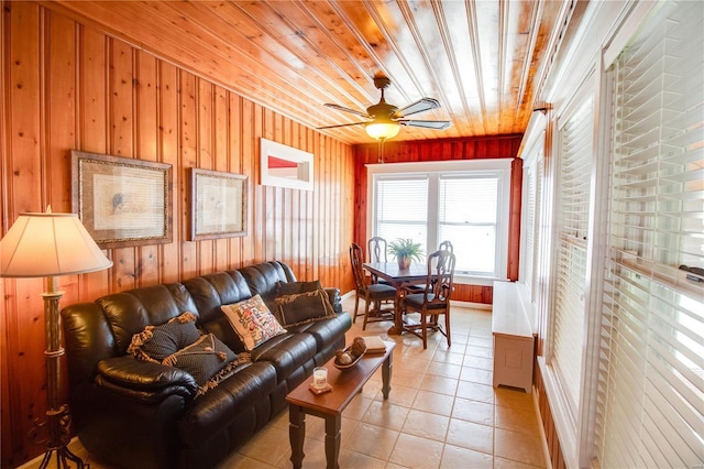 tiled living room featuring ceiling fan, wooden walls, and wood ceiling