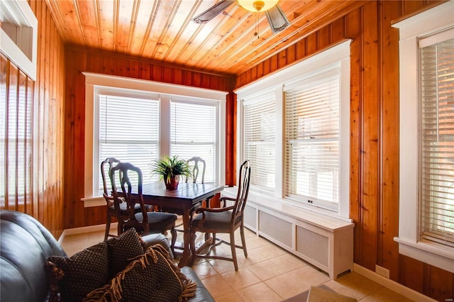 tiled dining area featuring a healthy amount of sunlight and wooden walls