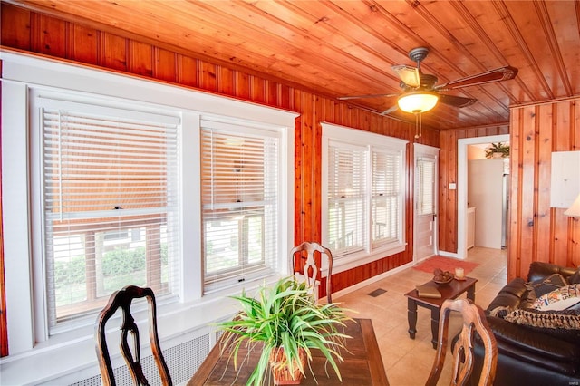 dining area with light tile patterned floors, wood ceiling, wooden walls, and ceiling fan