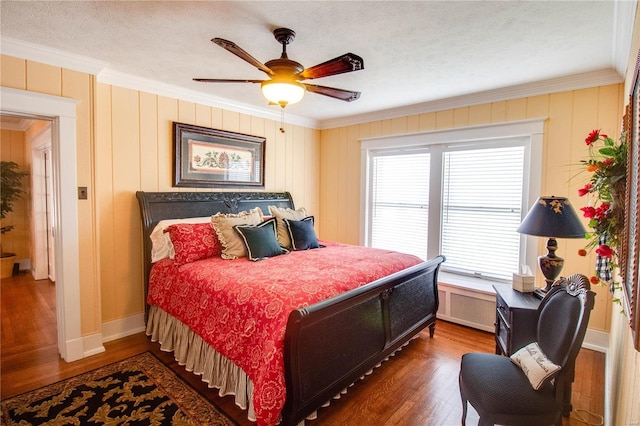 bedroom with a textured ceiling, ornamental molding, dark hardwood / wood-style floors, radiator heating unit, and ceiling fan