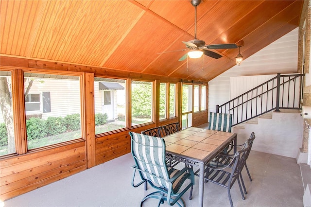 dining room with lofted ceiling, concrete flooring, wood walls, wooden ceiling, and ceiling fan