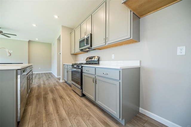 kitchen featuring sink, gray cabinetry, light wood-type flooring, appliances with stainless steel finishes, and ceiling fan