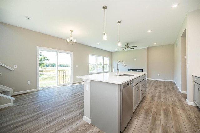 kitchen featuring sink, a kitchen island with sink, stainless steel dishwasher, and light hardwood / wood-style flooring