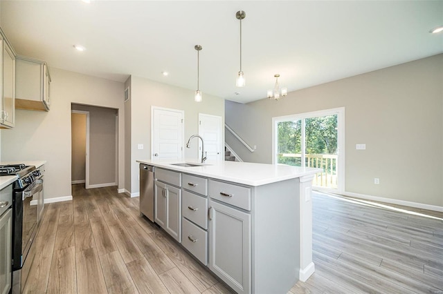 kitchen with sink, gas stove, gray cabinetry, a center island with sink, and stainless steel dishwasher