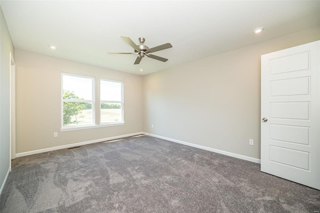 spare room with ceiling fan and dark colored carpet