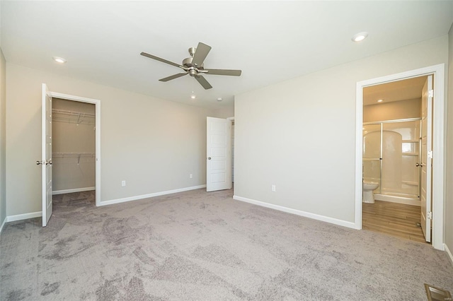 unfurnished bedroom featuring ceiling fan, connected bathroom, light carpet, a spacious closet, and a closet