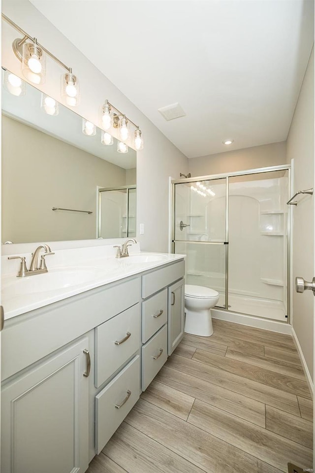 bathroom featuring vanity, a shower with shower door, and toilet