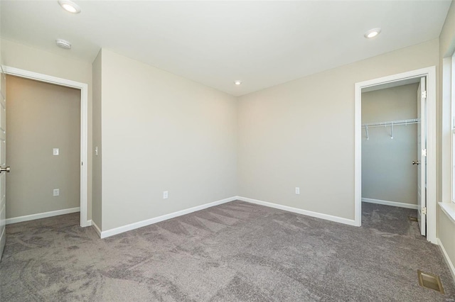 unfurnished bedroom with carpet floors, a walk in closet, and a closet